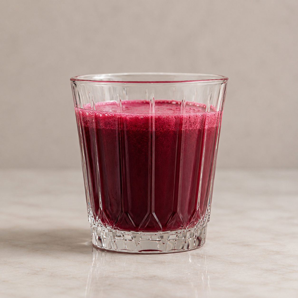 Crystal tumbler with beetroot juice on a minimalist table